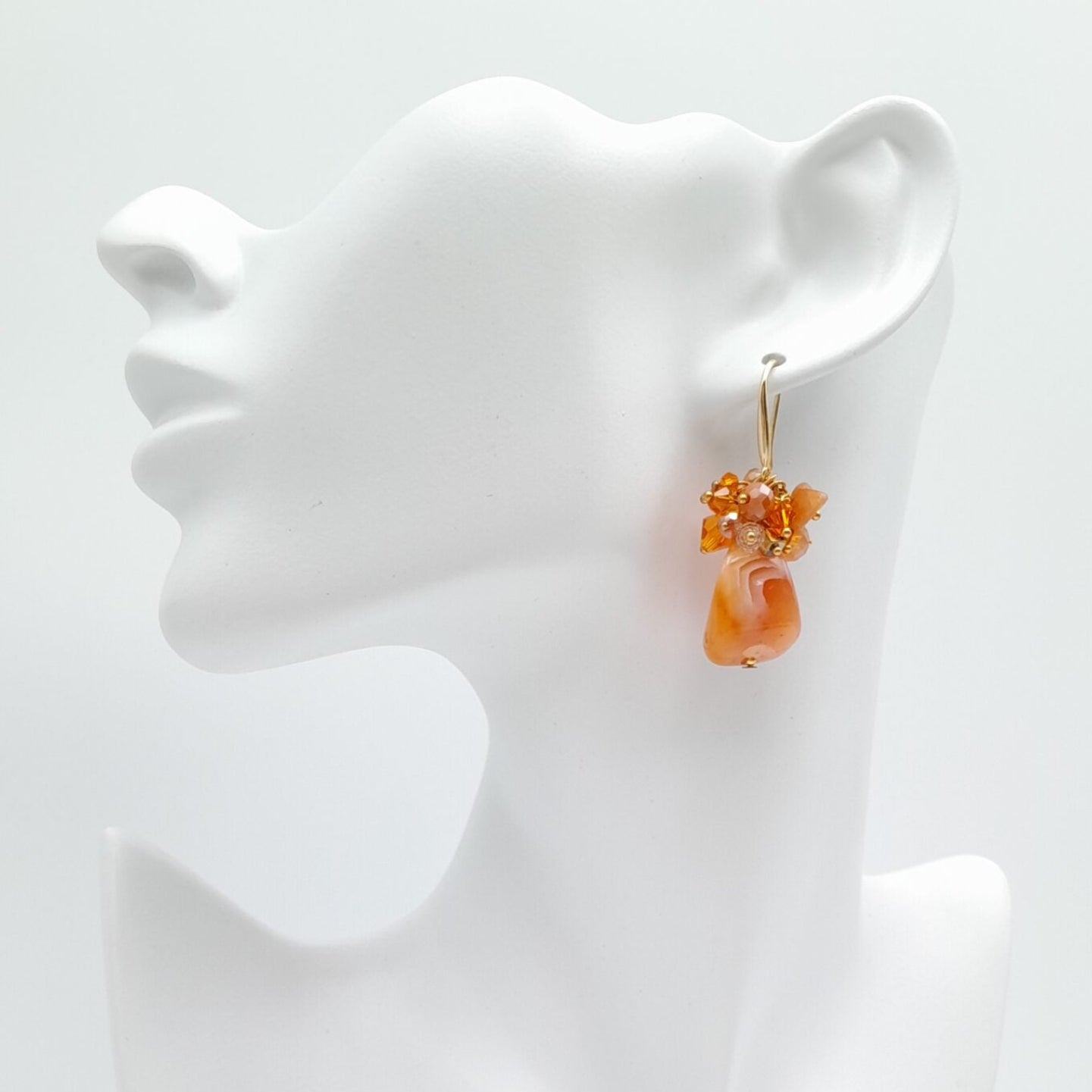Orange earrings on a white earring stand against a white background