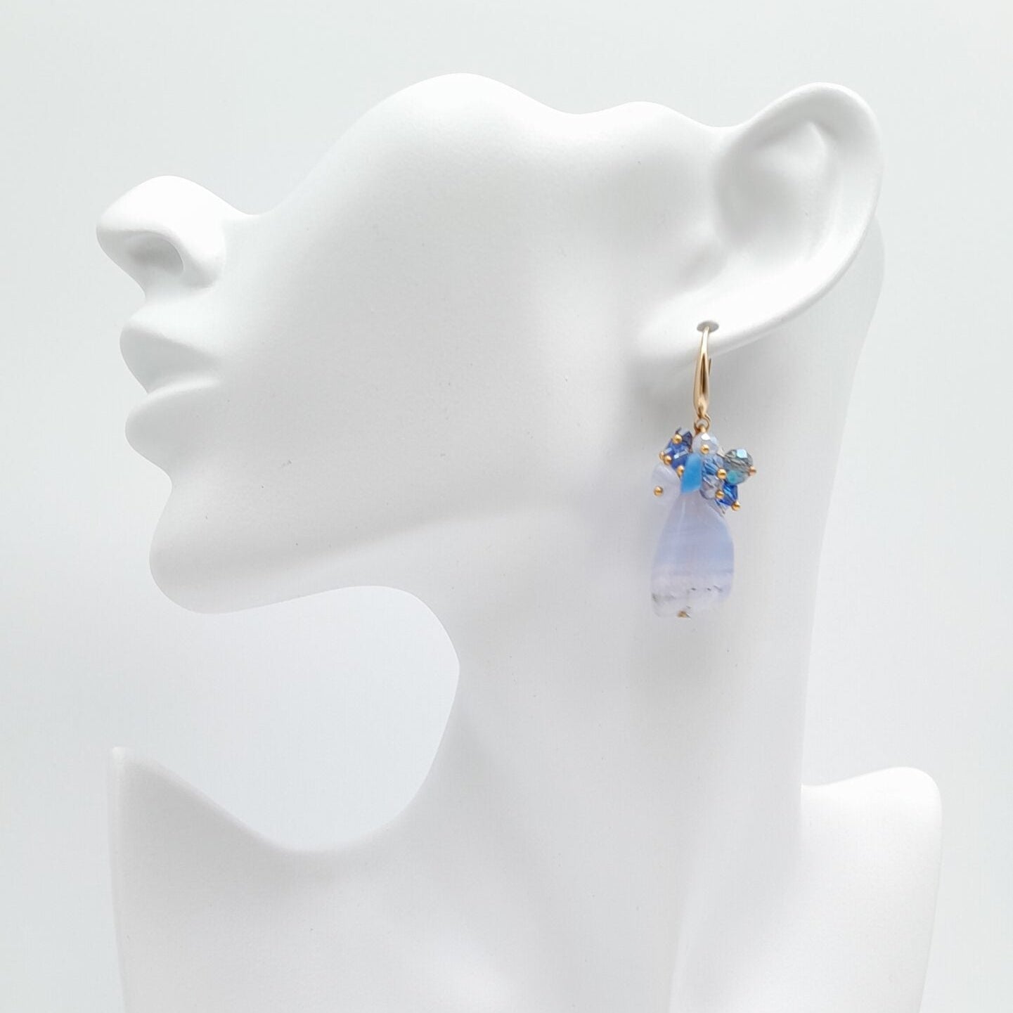 Earring displayed on a white mannequin bust against a white background