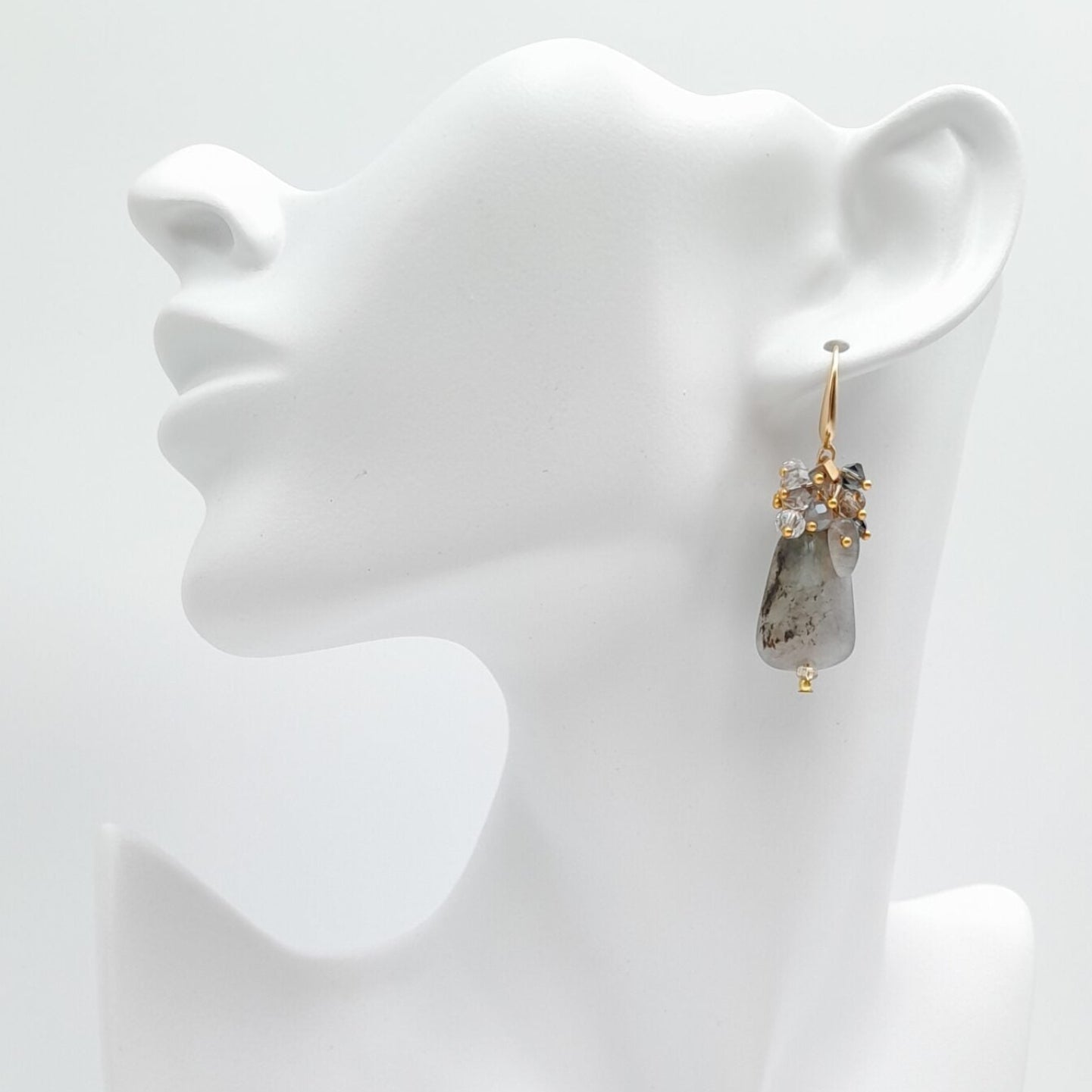 Earrings on a white mannequin bust against a white background