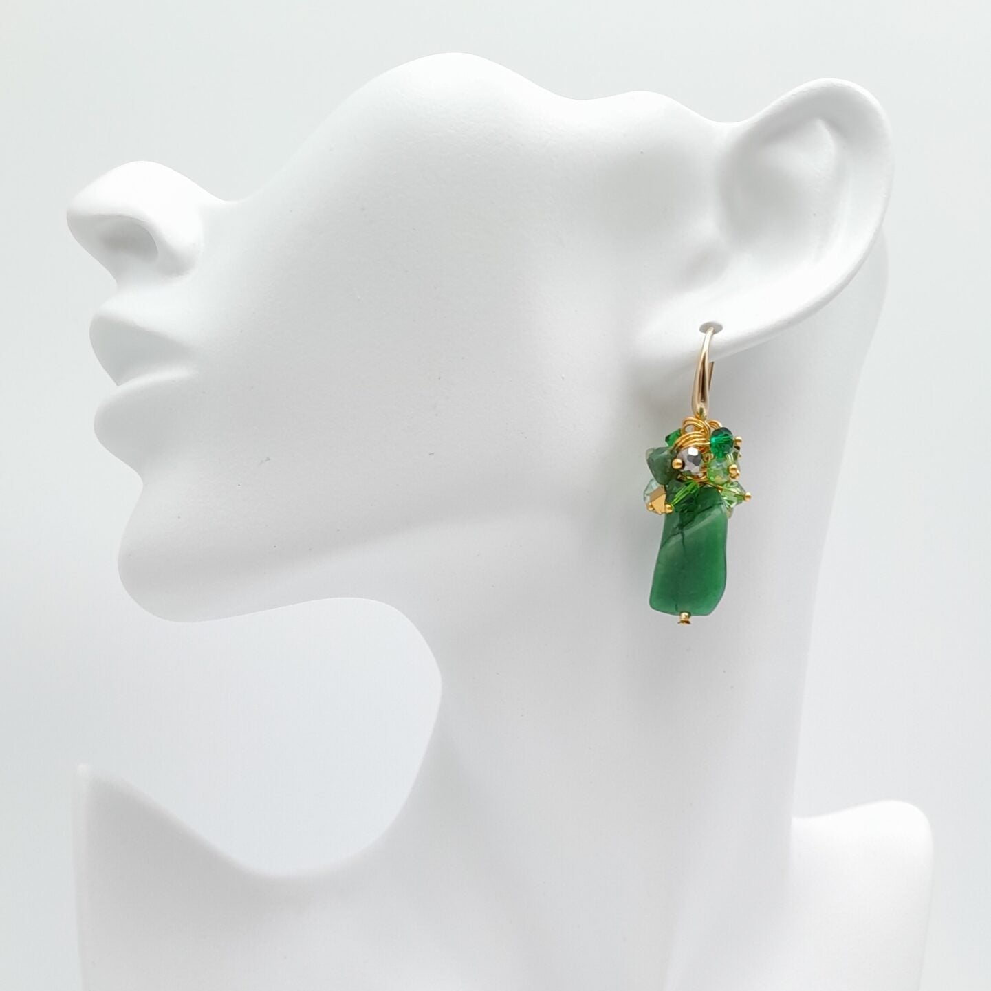 Green earrings on a white mannequin bust