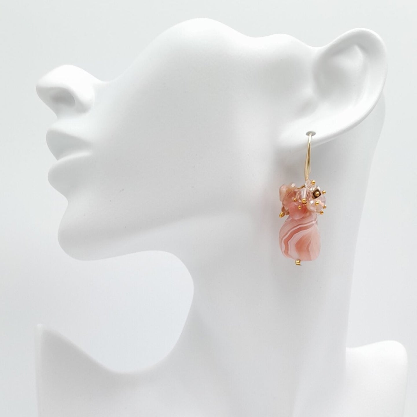 Pair of pink earrings on a white mannequin bust