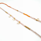 Beaded necklace with orange, pink, and gold beads on a white background