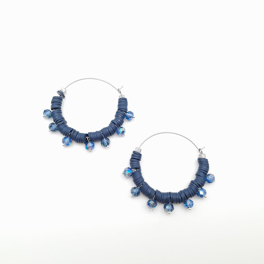 Pair of blue beaded hoop earrings on a white background
