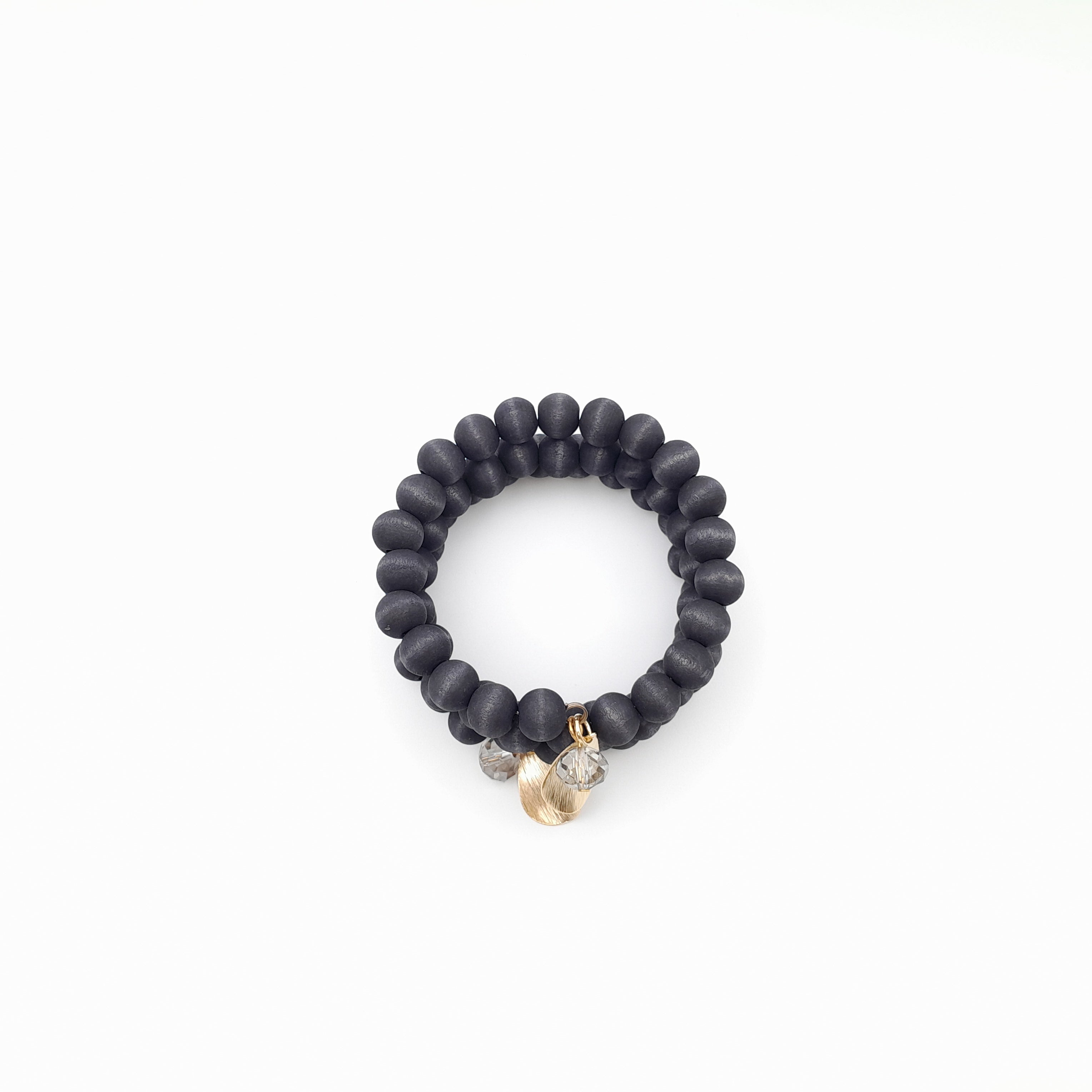 Black beaded bracelet with gold charm on a white background