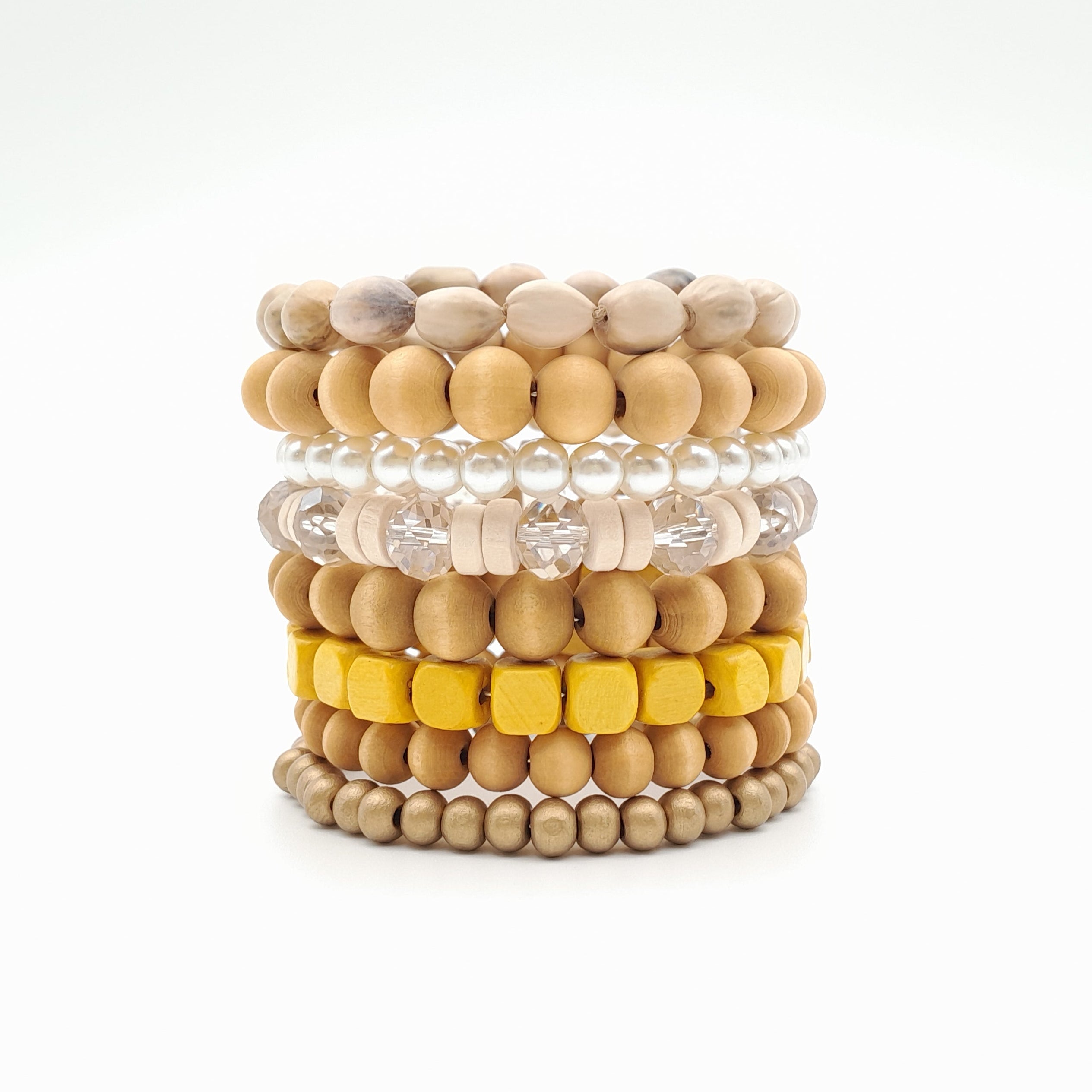 Stack of beaded bracelets in beige, yellow, and white on a white background
